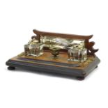 A Victorian desk standish with a central taper stick flanked by two glass inkwells, the base with