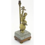 A 20thC table lamp decorated with cast figure of a putto holding aloft a bird, mounted upon a