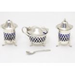 A silver three piece cruet set with pierced lattice decoration. With blue glass liners and