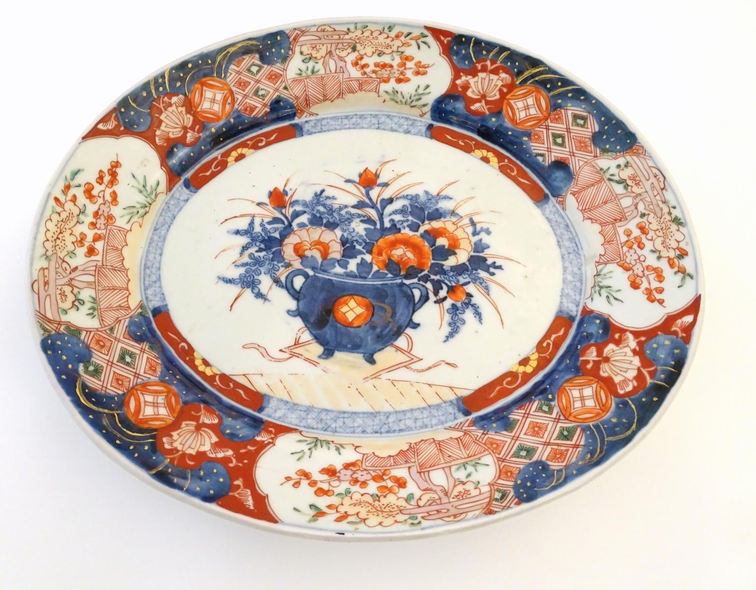 A Japanese Imari style plate, the centre decorated with a vase of flowers with a floral border.