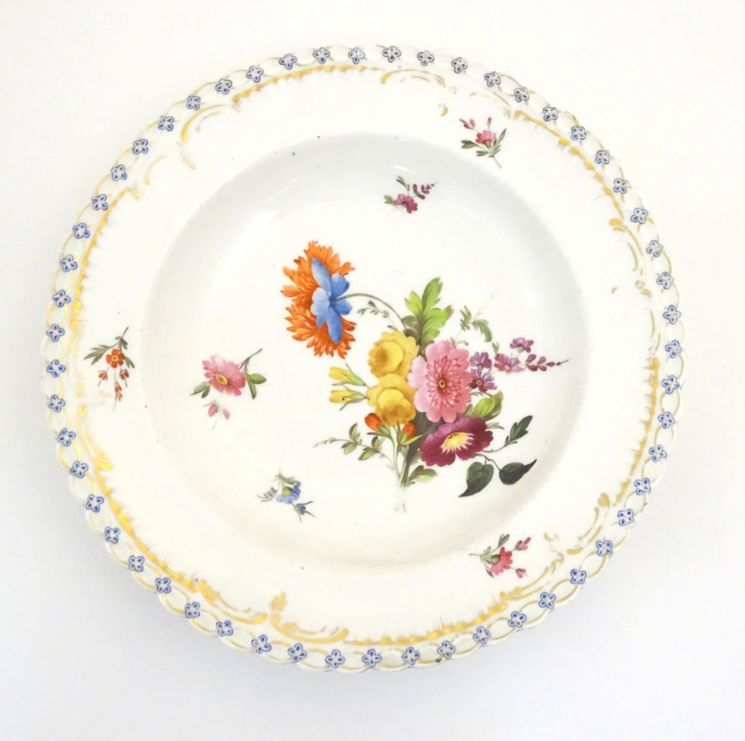 A 19thC porcelain soup dish with hand painted flower detail and gilt highlights. Approx. 10"