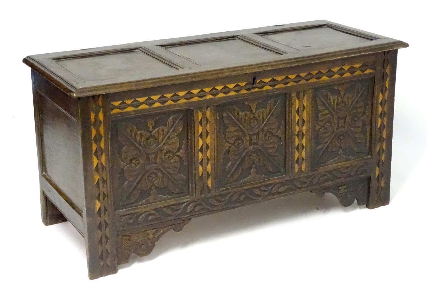 A 17thC oak three panel coffer with a moulded lid above carved panelling to the front with floral