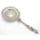 An ornate silver strainer / sifter spoon with figural detail to handle and floral and acanthus