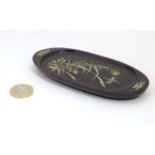 An oval lacquered pin dish with inlaid abalone decoration depicting a stylised dragonfly with