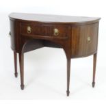 An early 20thC mahogany demi lune sideboard with a single short drawer flanked by cupboards with