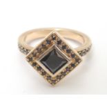 A 14ct rose gold ring set with central princess cut black diamond bordered by round brilliant cut