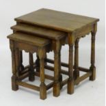 A nest of three early 20thC oak tables with shaped apron and nulled friezes above four turned