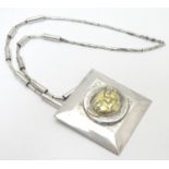 An unusual silver necklace with large square pendant with hammered decoration and silver gilt face