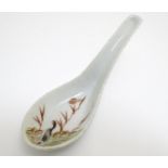 A Chinese soup spoon with hand painted decoration depicting a goose / bird in a wetland landscape.
