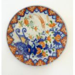 An Oriental plate in the Imari palette decorated with flowers, foliage and an Asiatic pheasant.