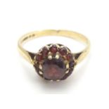 A 9ct gold ring set with garnet cluster ring, the central stone surrounded by twelve smaller stones.