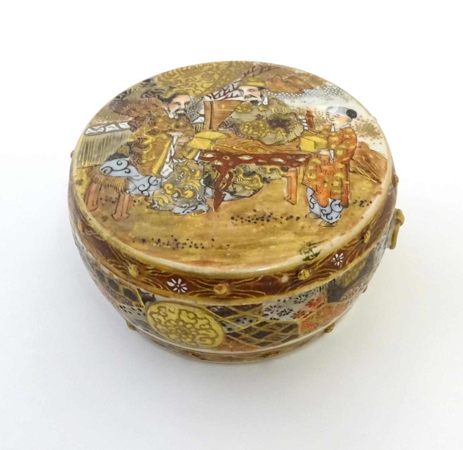 A Japanese Satsuma pot and cover. The cover decorated with a landscape scene with two scholar