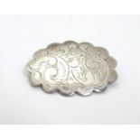 A silver brooch of scalloped oval form with engraved decoration, marked Sterling Thailand. 1 1/4"