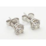 A pair of white gold stud earrings set with diamond solitaires. The diamond approximately 1/8"