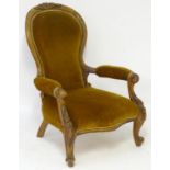 A late 19thC mahogany open armchair with carved cresting rail above a spoon back and swept arms,