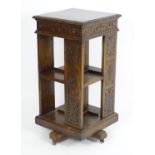 An early 20thC oak revolving bookcase with a moulded squared top above a lozenge carved floral frame