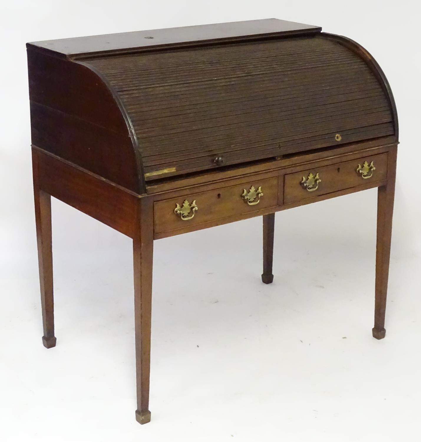 A late 18thC / early 19thC mahogany tambour fronted desk with a quarter cylinder top opening to show