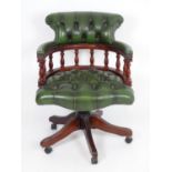 A late 20thC captains chair with deep buttoned leather upholstery, turned finial supports and having