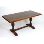 An early / mid 20thC oak draw leaf dining table with a rectangular top above two cup and cover