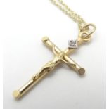 A 9ct gold pendant formed as a crucifix set with single diamond on a 18" chain. The pendant 1/4"