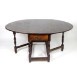 An 18thC oak drop leaf table opening to form an oval table top, the table having a single frieze