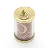 A 9ct gold novelty pendant / charm of cylindrical form with rolled 10 shilling note to centre.