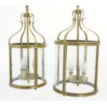 Two brass pendant hall lights of lantern form each with four glass panels. The largest aprox 23"