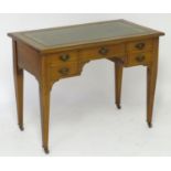 An early 20thC Arts & Crafts style walnut desk with a gold tooled leather top above a five drawer