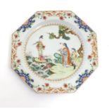A Chinese plate of octagonal form decorated in famille rose depicting figures in a coastal landscape