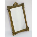A late 19thC / early 20thC mirror with a giltwood and gesso frame having carved and moulded