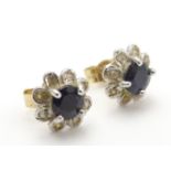 A pair of 9ct gold stud earrings set with central blue stone bordered by chip set diamonds.