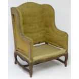 An 18thC French Louis XV wingback armchair, with a shaped top and sides, a walnut frame with moulded