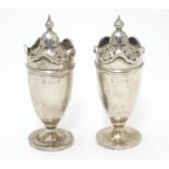 A pair of silver pepperettes with wavy-edged rims. Hallmarked Birmingham 1923 maker Martin Hall & Co