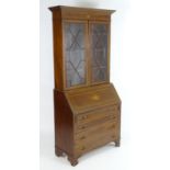 An early 20thC mahogany bureau bookcase with a moulded cornice above two astragal glazed doors and