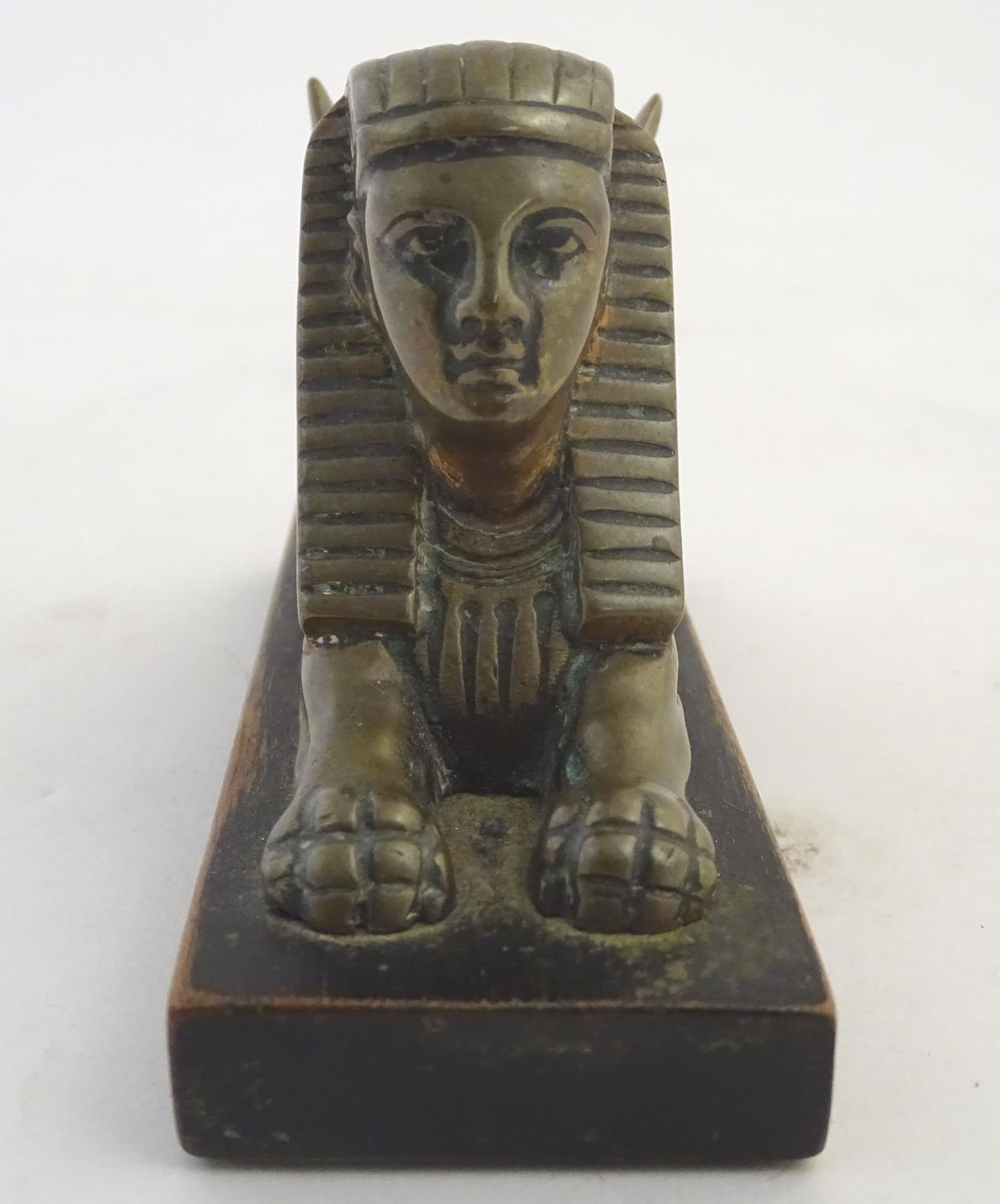 A 20thC paperweight formed as a winged sphinx with the head of a pharaoh on a rectangular wooden - Image 3 of 7