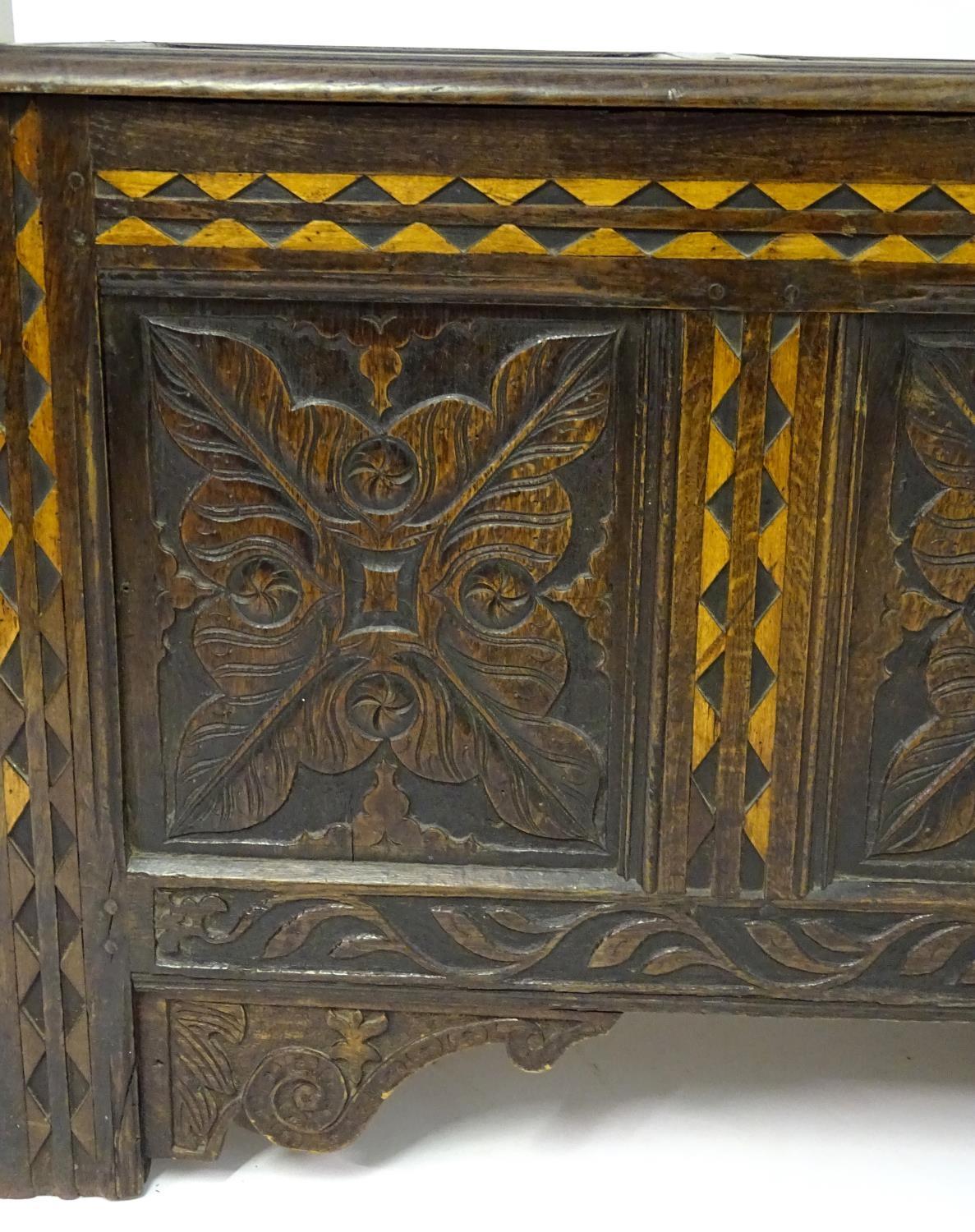 A 17thC oak three panel coffer with a moulded lid above carved panelling to the front with floral - Bild 2 aus 11