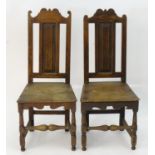 A pair of 17thC oak side chairs with shaped top rails, panelled backs and seats, standing on