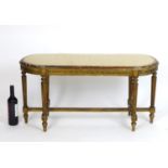 A late 19thC / early 20thC giltwood stool with an oval upholstered top above a moulded frame and six