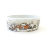 A Chinese circular dish with hand painted decoration depicting a winter snowy landscape scene with