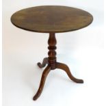 An early 19thC mahogany tripod table, having an oval shaped top above a turned stem and three