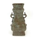 An Oriental cast bronze vase with twin mask handles with a looped ring, the body decorated with