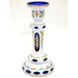 An early 20thC Bohemian blue glass candlestick, overlaid with white base, gilt banding and floral