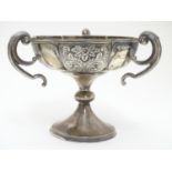 A silver pedestal dish with three handles and embossed decoration. Hallmarked Birmingham 1906