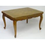 An early 20thC cherry wood dining table with a parquetry style top and draw leaves to each side,