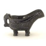 An Oriental carved stone vessel with a pouring spout, beast formed handle and four feet. The side