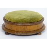 A late 19thC footstool with a circular overstuffed top above a moulded frame and four squat bun
