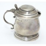 A silver mustard pot on stepped base, with blue glass liner within. Hallmarked Birmingham 1921 maker