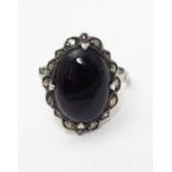 A silver ring set with black onyx cabochon bordered by marcasites. Ring approx size O. Please Note -