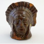 A 19thC treacle and slip glazed terracotta window stop formed as the bust of Native American