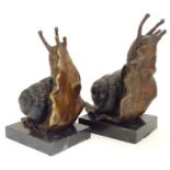 A pair of 20thC cast bronze bookends modelled as snails, each on a rectangular marble base